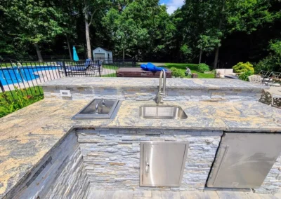 outdoor kitchen made in stone veneer an granite countertop with sink refrigeration storage drink cooler